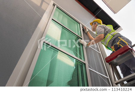 Construction worker repairing the sliding window. Open cap of adjust rail wheel. Construction worker repairing the sliding window. Open cap of adjust rail wheel. 113410224