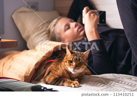 Teenager uses smartphone while travelling with his cat on a train. 113410251