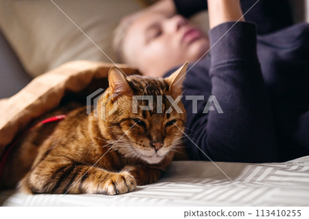 Teenage boy travelling with a cat in the sleep wagon of passenger train. Teenage boy travelling with a cat in the sleep wagon of passenger train. 113410255