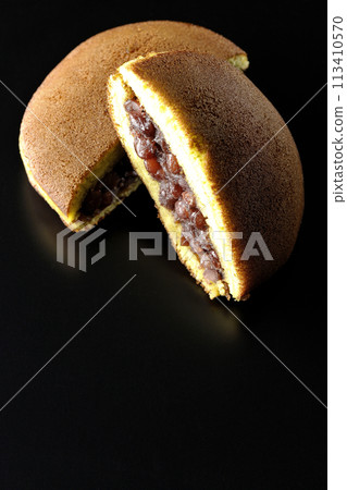 Cut dorayaki photographed against a black background 113410570