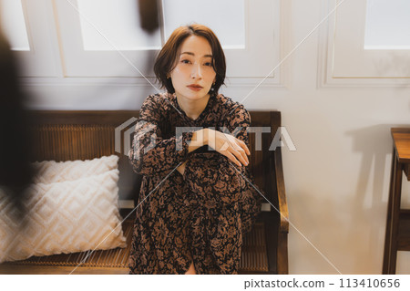 Middle-aged woman sitting on a sofa in a room 113410656