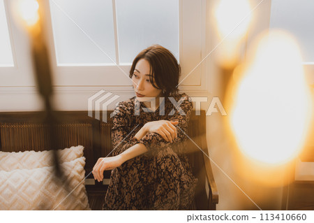 Middle-aged woman sitting on a sofa in a room Middle-aged woman sitting on a sofa in a room 113410660