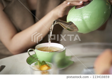 asian woman pouring tea into  a teacup 113410859