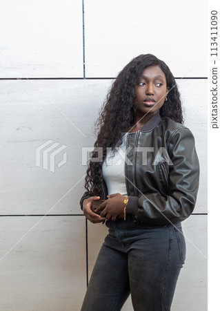 Urban Style African Woman in Leather Jacket Leaning Against a Concrete Wall Urban Style African Woman in Leather Jacket Leaning Against a Concrete Wall 113411090
