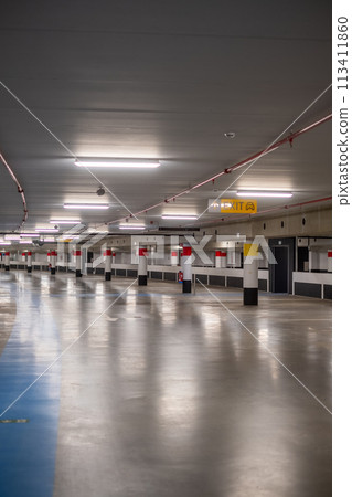 Empty Underground Parking Lot with Reflective Floor and Illuminated Rows 113411860