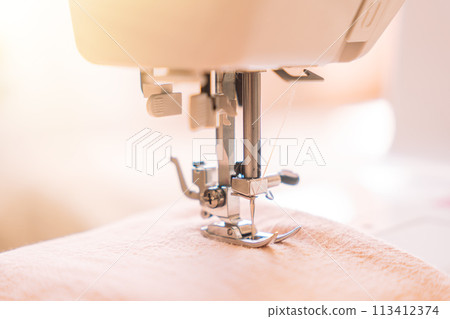 Close-up of a foot from a white sewing machine Close-up of a foot from a white sewing machine 113412374