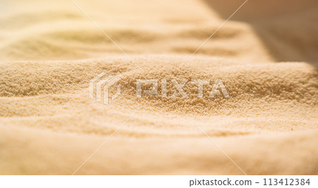 Yellow clean sand with wavy patterns under sunlight 113412384
