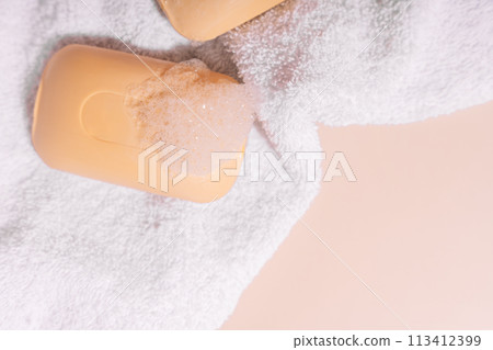 Two soap bars of soap on a white towel on a beige background Two soap bars of soap on a white towel on a beige background 113412399