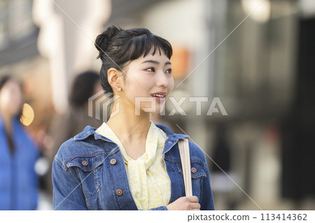 Smiling young woman walking down the street 113414362