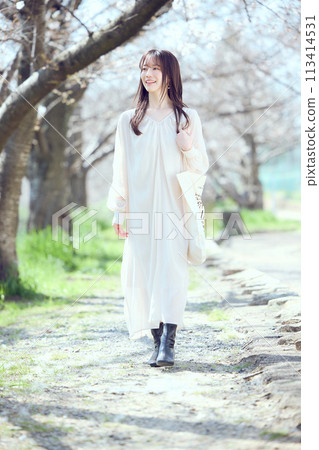 A woman walking along a riverbed of cherry blossom trees A woman walking along a riverbed of cherry blossom trees 113414531