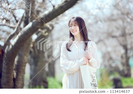 A woman walking along a riverbed of cherry blossom trees A woman walking along a riverbed of cherry blossom trees 113414637