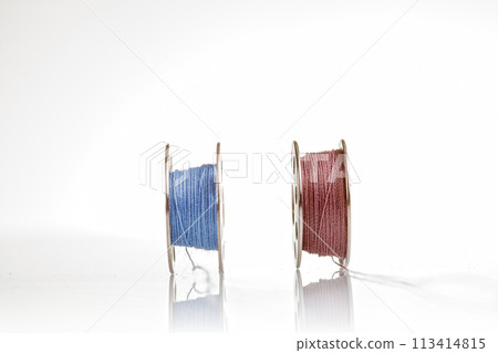 spools of blue and pink thread on a white background spools of blue and pink thread on a white background 113414815