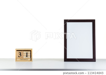 Wooden calendar 31 January with frame for photo on white table and background 113414843