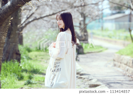 一個女人沿著櫻花樹河床散步 一個女人沿著櫻花樹河床散步 113414857