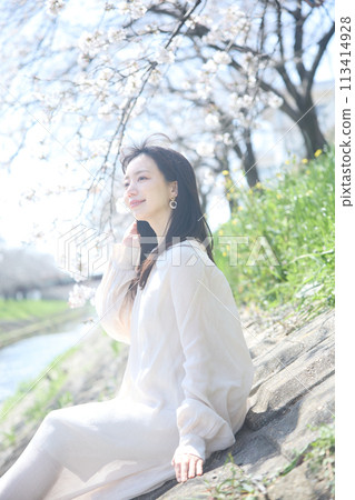 A woman enjoying cherry blossom viewing by the river 113414928