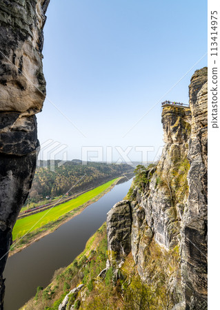 The Bastei Bridge spans rocky pinnacles above the Elbe River, or Labe River, amidst the lush terrain of Saxon Switzerland National Park. Germany The Bastei Bridge spans rocky pinnacles above the Elbe River, or Labe River, amidst the lush terrain of Saxon Switzerland National Park. Germany 113414975
