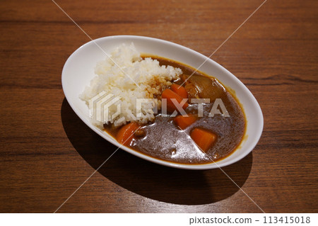 Japanese curry with rice in a white plate on a wooden table Japanese curry with rice in a white plate on a wooden table 113415018