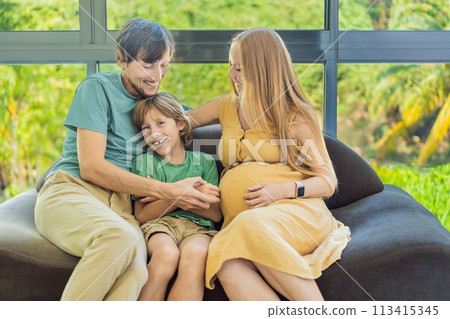 Cozy family time at home as pregnant mom, dad, and son enjoy shared moments on the sofa, creating heartwarming memories and cherishing their time together 113415345