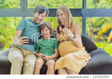 Heartwarming family video call as expecting mom, dad, and son share the excitement, displaying ultrasound photos and connecting virtually during the pregnancy journey 113415347