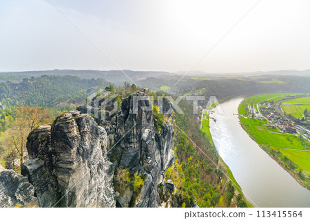 The Bastei sandstone formations tower above the Elbe River amidst the greenery of Saxon Switzerland National Park. Germany The Bastei sandstone formations tower above the Elbe River amidst the greenery of Saxon Switzerland National Park. Germany 113415564