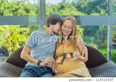 In a touching moment, the pregnant woman and father connect via video call, sharing the joy as they hold up an ultrasound photo, bridging the distance with the anticipation of their baby's arrival In a touching moment, the pregnant woman and father connect via video call, sharing the joy as they hold up an ultrasound photo, bridging the distance with the anticipation of their baby's arrival 113415597