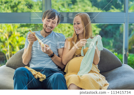 In a heartwarming scene, the future mom and dad hold their unborn baby's clothes in their hands, savoring the joy of anticipation and shared excitement for their little one's arrival In a heartwarming scene, the future mom and dad hold their unborn baby's clothes in their hands, savoring the joy of anticipation and shared excitement for their little one's arrival 113415734