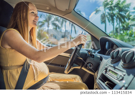 Pregnant woman driving with safety belt on in the car. Confident and capable, a pregnant woman takes the wheel, driving with care and determination as she navigates the journey of motherhood 113415834