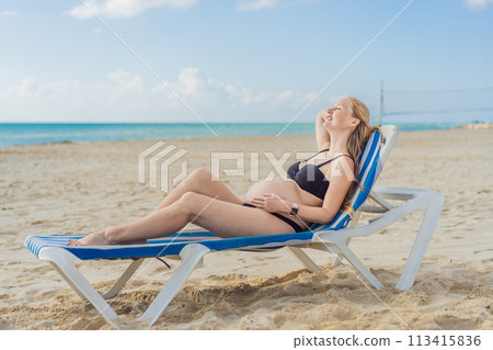 Basking in seaside tranquility, a pregnant woman lounges on a sun lounger, embracing the soothing ambiance of the beach for a moment of serene relaxation 113415836