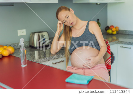 A tired pregnant woman sits in the kitchen after cleaning. Health and vitality of a pregnant woman 113415844