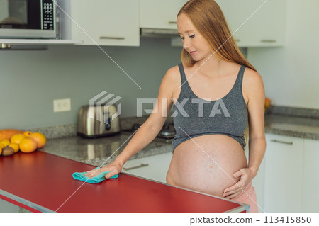 Efficient and dedicated, a pregnant woman tackles kitchen chores, ensuring a clean and organized space, exemplifying resilience and care during her pregnancy 113415850