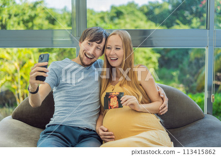 In a touching moment, the pregnant woman and father connect via video call, sharing the joy as they hold up an ultrasound photo, bridging the distance with the anticipation of their baby's arrival In a touching moment, the pregnant woman and father connect via video call, sharing the joy as they hold up an ultrasound photo, bridging the distance with the anticipation of their baby's arrival 113415862