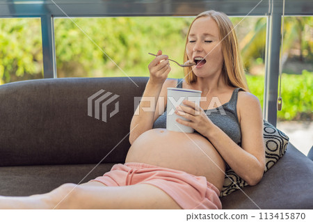 Happy pregnant young woman eating ice cream Happy pregnant young woman eating ice cream 113415870