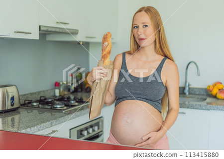 Pregnant woman eating bread in the kitchen. Exploring the impact of gluten during pregnancy: understanding the potential benefits and risks for maternal health and fetal development 113415880