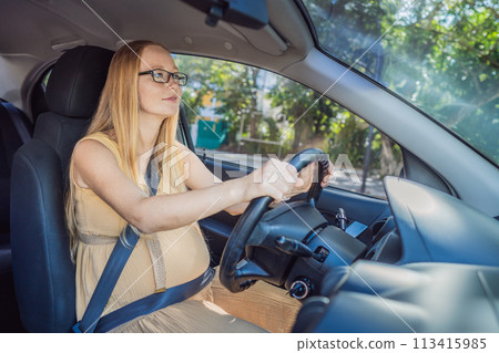 Pregnant woman driving with safety belt on in the car. Confident and capable, a pregnant woman takes the wheel, driving with care and determination as she navigates the journey of motherhood Pregnant woman driving with safety belt on in the car. Confident and capable, a pregnant woman takes the wheel, driving with care and determination as she navigates the journey of motherhood 113415985