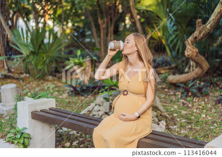 pregnant woman enjoys a cup of coffee outdoors, blending the simple pleasures of nature with the comforting warmth of a beverage during her pregnancy pregnant woman enjoys a cup of coffee outdoors, blending the simple pleasures of nature with the comforting warmth of a beverage during her pregnancy 113416044