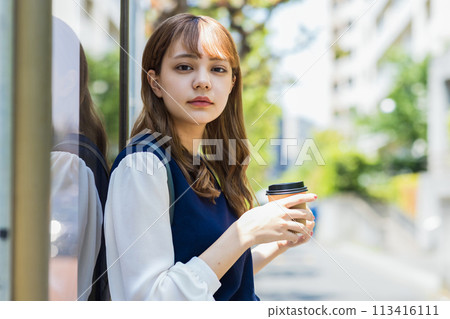 Young woman drinking coffee outdoors Young woman drinking coffee outdoors 113416111
