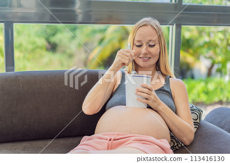 Happy pregnant young woman eating ice cream 113416130