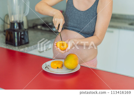 A skillful pregnant woman delicately cuts into a ripe mango, savoring a moment of culinary joy and nourishing her pregnancy with a fresh and flavorful treat A skillful pregnant woman delicately cuts into a ripe mango, savoring a moment of culinary joy and nourishing her pregnancy with a fresh and flavorful treat 113416169