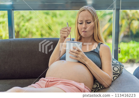 Happy pregnant young woman eating ice cream Happy pregnant young woman eating ice cream 113416223