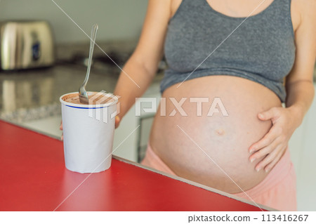 Happy pregnant young woman eating ice cream Happy pregnant young woman eating ice cream 113416267