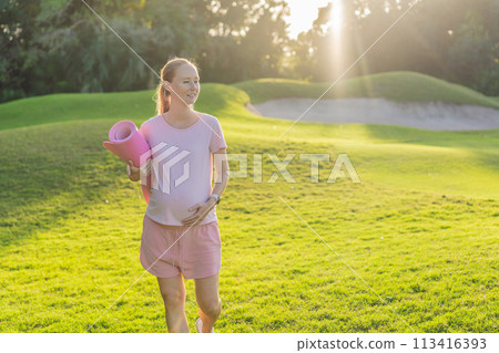 Energetic pregnant woman takes her workout outdoors, using an exercise mat for a refreshing and health-conscious outdoor exercise session 113416393