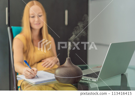 Expectant woman enhances work environment, using an aroma diffuser for a soothing atmosphere during pregnancy 113416415