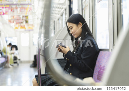 High school girl looking at smartphone screen on train - Image of commuting to school by train 113417052