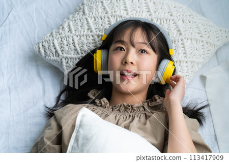 戴著耳機躺在床上的女孩 戴著耳機躺在床上的女孩 113417909