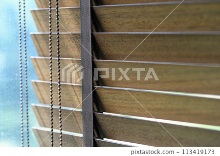 Close-up brown wooden blinds. lighting range control sunlight coming from a window. decoration interior. Modern jalousie. 113419173