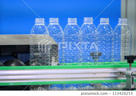 The empty drinking water bottles on the conveyor belt for filling process. The empty drinking water bottles on the conveyor belt for filling process. 113420253