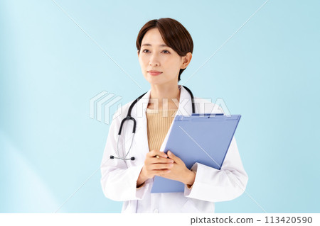 A woman in a white coat holding a medical record 113420590
