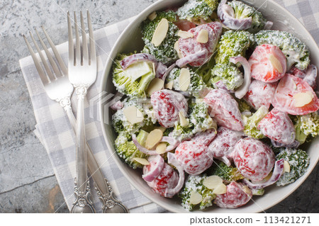 Healthy summer broccoli salad with strawberries, red onions and almonds dressed with yogurt close-up in a plate. Horizontal top view 113421271