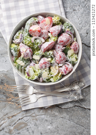 Fresh broccoli salad with strawberries, red onions and almonds dressed with yogurt close-up in a plate. Vertical top view 113421272