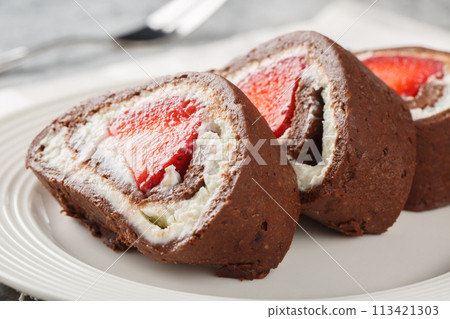 Pieces of chocolate cake roll with strawberries and cream cheese close-up. Horizontal Pieces of chocolate cake roll with strawberries and cream cheese close-up. Horizontal 113421303